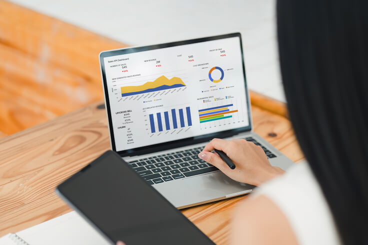 woman typing on a laptop with charts onscreen